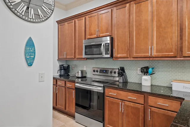 a kitchen with stainless steel appliances granite countertop a sink a stove top oven a clock and cabinets