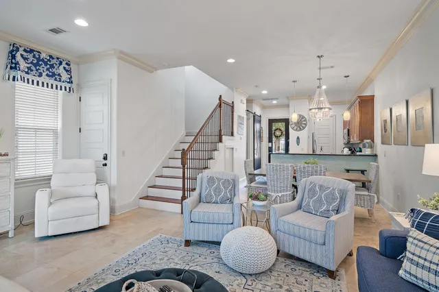 a living room with furniture and a dining table with white kitchen