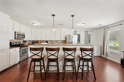 a kitchen with stainless steel appliances kitchen island granite countertop a dining table chairs and granite counter tops