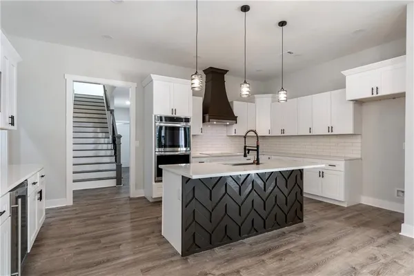 a kitchen with stainless steel appliances granite countertop a sink a stove and a wooden floors