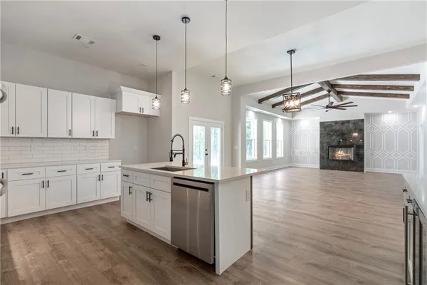 a kitchen with stainless steel appliances granite countertop a sink a stove and a wooden floor