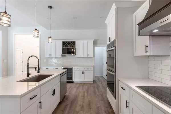 a kitchen with white cabinets a sink stove and refrigerator