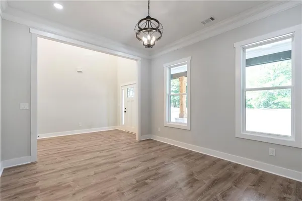 a view of an empty room with a window and wooden floor