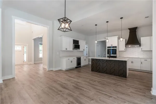 a large kitchen with stainless steel appliances kitchen island granite countertop a stove a sink a refrigerator and a wooden floors