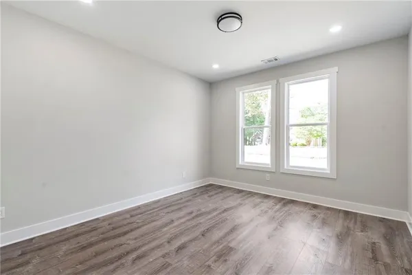 an empty room with wooden floor and windows