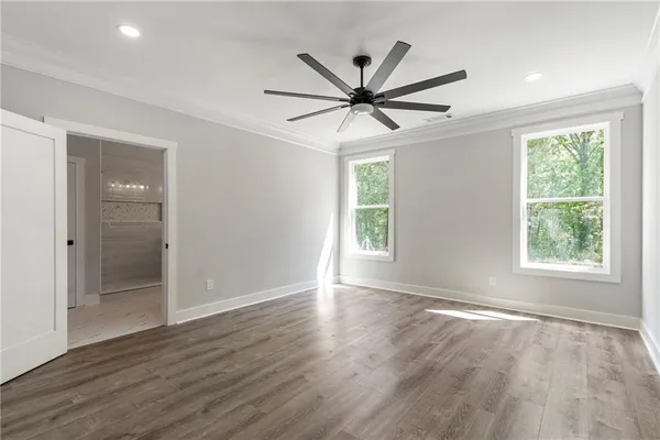 an empty room with wooden floor fan and windows