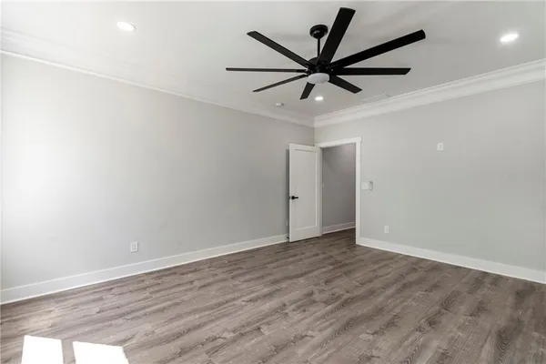 an empty room with wooden floor fan and windows