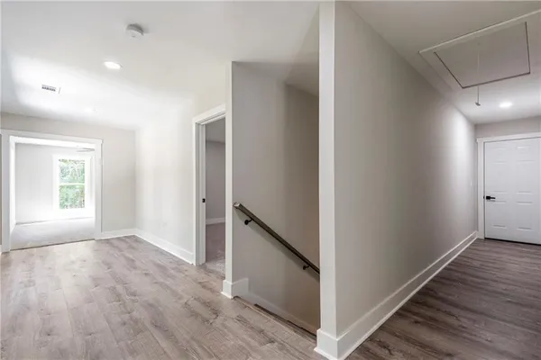 a view of hallway with window and wooden floor
