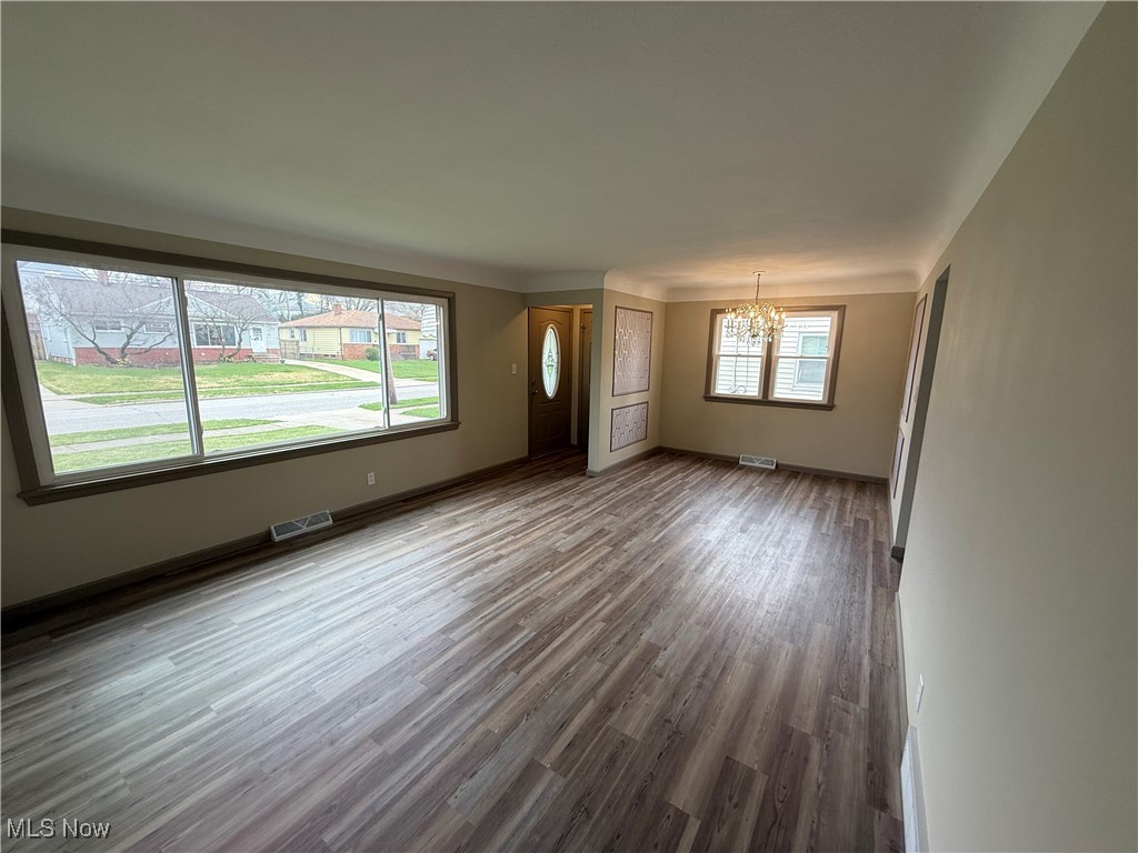 9417 Alexander Road Garfield Heights, OH 44125 - Photo 13 of 38 Unfurnished living room with baseboards, wood finished floors, a notable chandelier, and visible vents