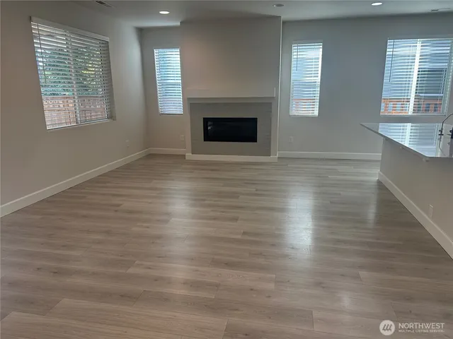 an empty room with wooden floor fireplace and windows