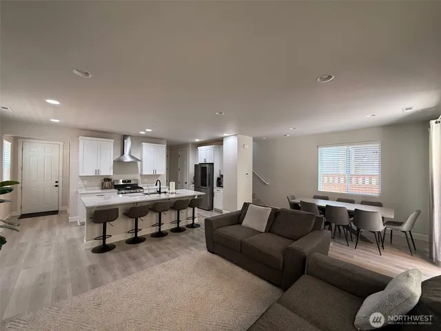 a living room with furniture a table and kitchen view