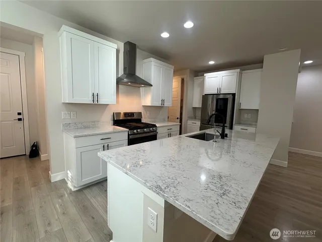 a kitchen with kitchen island granite countertop a sink a counter top space appliances and cabinets