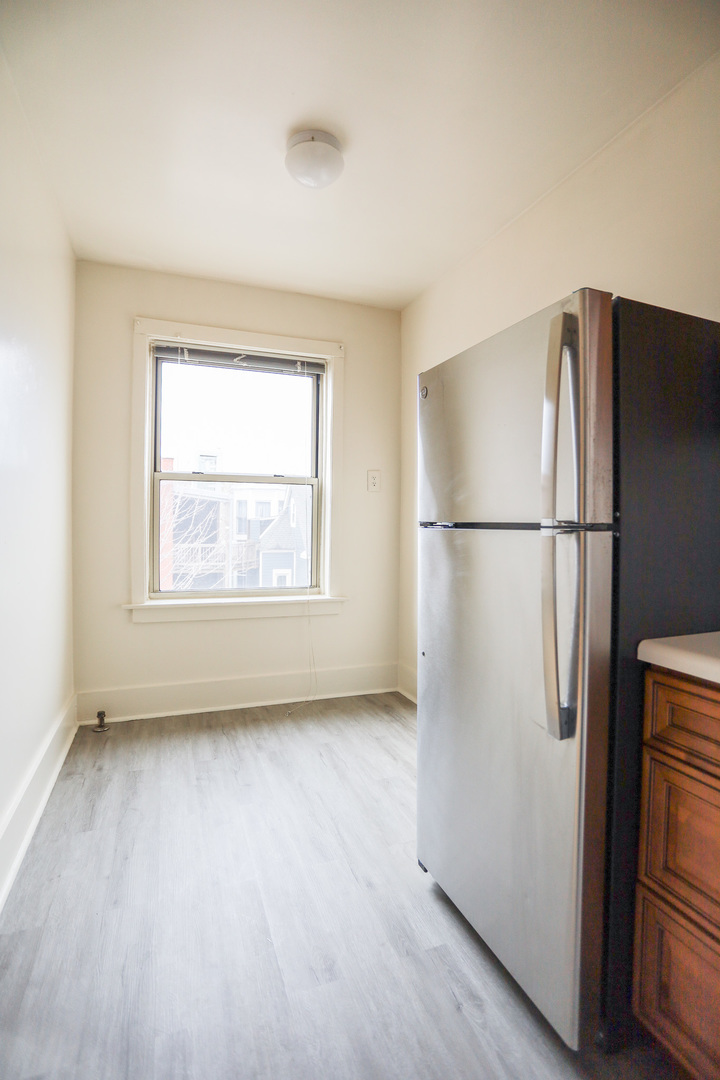 1100 West Roscoe Street, Unit 32 Chicago, IL 60657 - Photo 3 of 8 a view of a kitchen with a refrigerator cabinet a fridge and a window