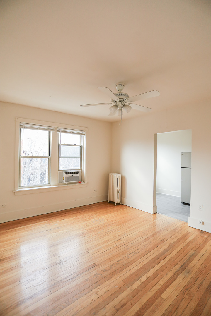1100 West Roscoe Street, Unit 32 Chicago, IL 60657 - Photo 6 of 8 a view of an empty room with wooden floor and a window