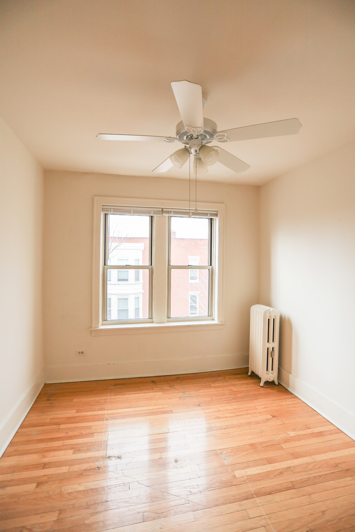 1100 West Roscoe Street, Unit 32 Chicago, IL 60657 - Photo 7 of 8 an empty room with a window and ceiling fan