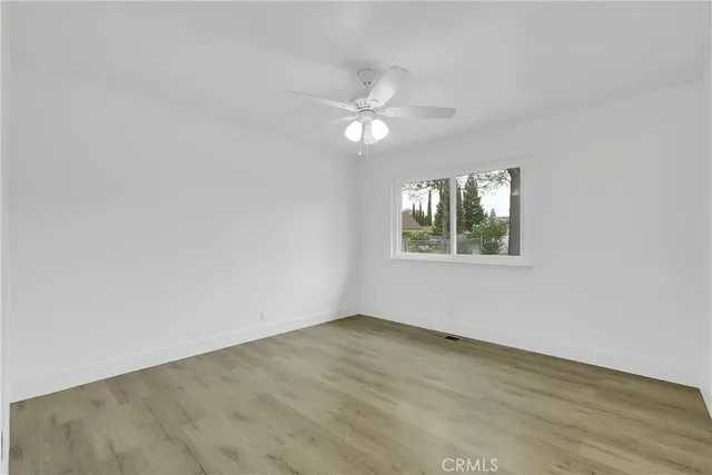 an empty room with wooden floor ceiling fan and window