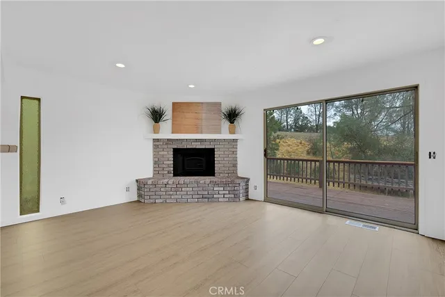 a view of empty room with floor to ceiling window and fireplace