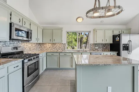 a kitchen with stainless steel appliances granite countertop a stove sink and cabinets