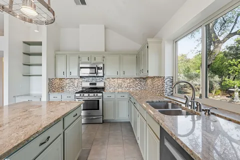 a kitchen with stainless steel appliances granite countertop a sink a stove and cabinets