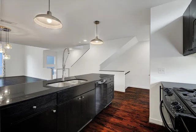 a kitchen with stainless steel appliances granite countertop a sink a stove and a wooden floors