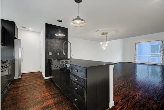 a kitchen with stainless steel appliances granite countertop a refrigerator and a wooden floor