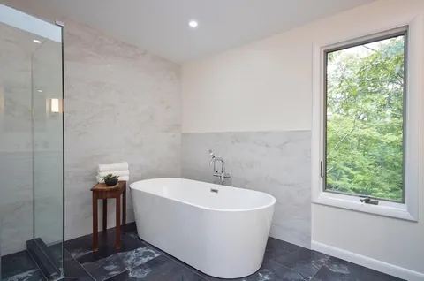 a white bath tub sitting in a bathroom next to a window