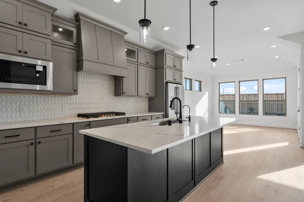 a kitchen with stainless steel appliances granite countertop a sink a stove and a wooden floors