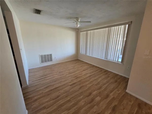 a view of a hallway with wooden floor and a ceiling fan