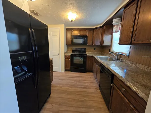 a kitchen with stainless steel appliances granite countertop a refrigerator a stove and a sink