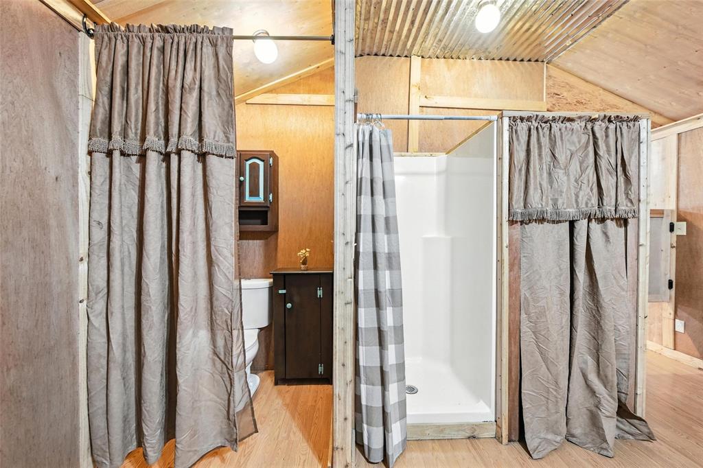 454 Bear Ridge Road Bowie, TX 76230 - Photo 15 of 36 Bathroom featuring vaulted ceiling, a stall shower, and wood finished floors