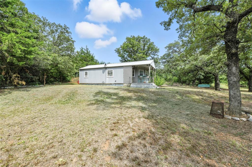 454 Bear Ridge Road Bowie, TX 76230 - Photo 19 of 36 Rear view of house with a lawn, a metal roof, and a porch