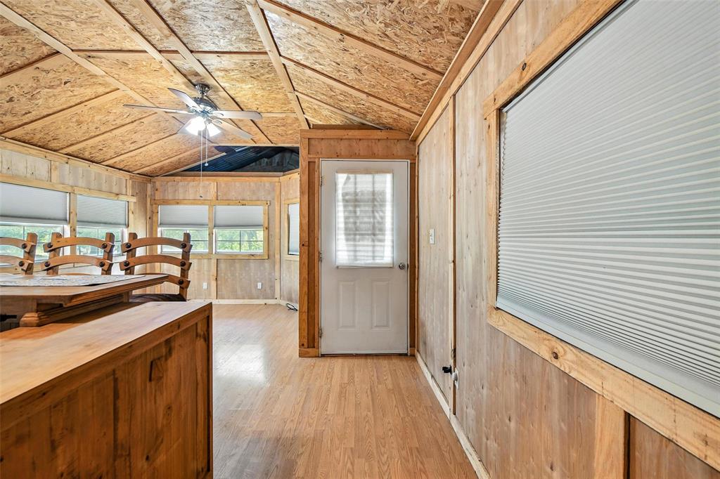 454 Bear Ridge Road Bowie, TX 76230 - Photo 3 of 36 Doorway to outside featuring lofted ceiling, wooden walls, light wood-type flooring, and a ceiling fan