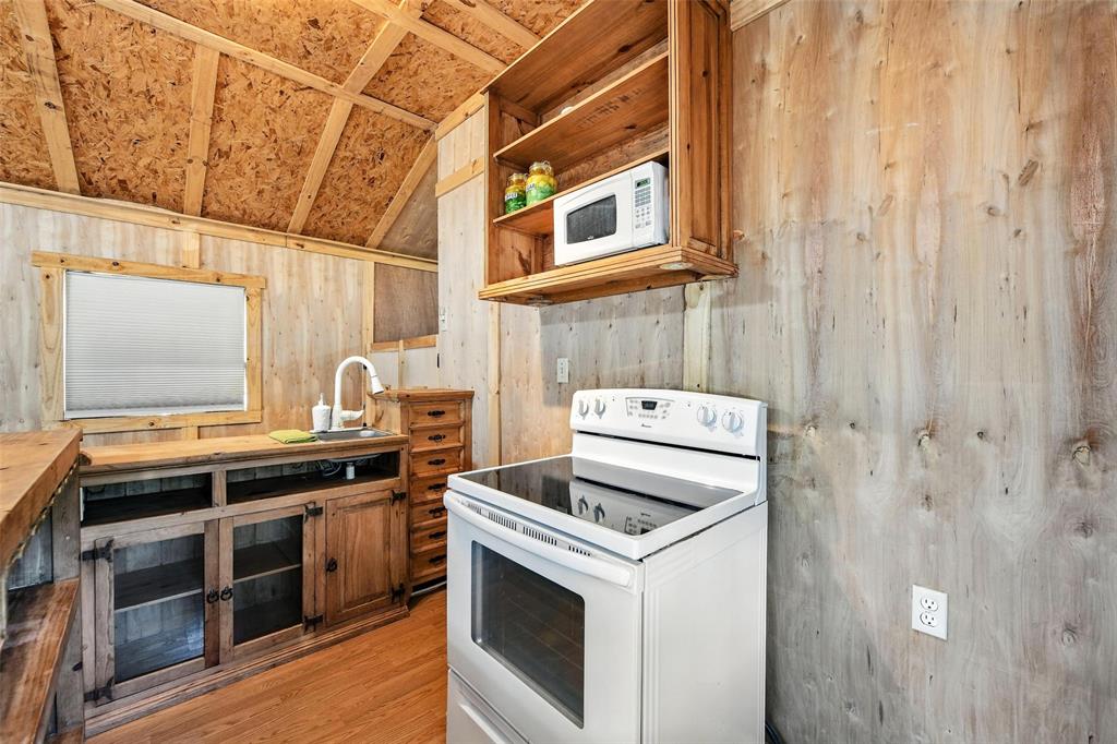 454 Bear Ridge Road Bowie, TX 76230 - Photo 8 of 36 Kitchen with white appliances, lofted ceiling, wood walls, light wood-style floors, and open shelves