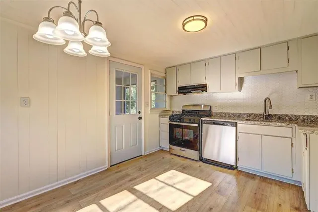 a kitchen with granite countertop a stove a sink and a microwave