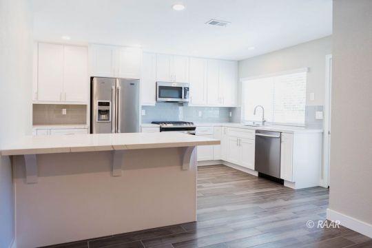 513 Suzanne Street Ridgecrest, CA 93555 - Photo 10 of 34 a kitchen with white cabinets and stainless steel appliances