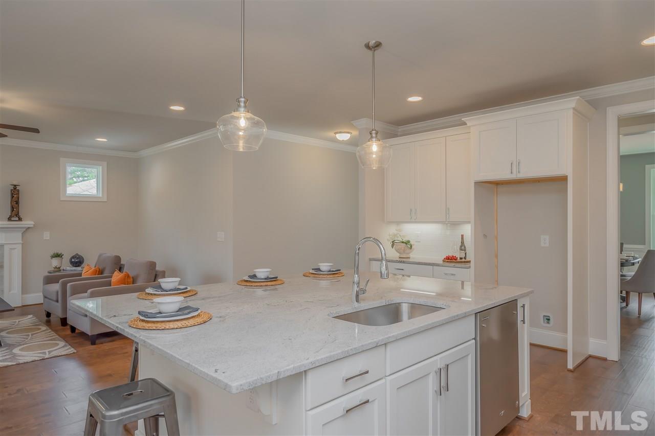 3911 Sue Lane Raleigh, NC 27604 - Photo 7 of 25 a kitchen with a sink dishwasher a dining table and chairs with wooden floor