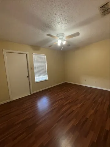 an empty room with wooden floor chandelier fan and windows