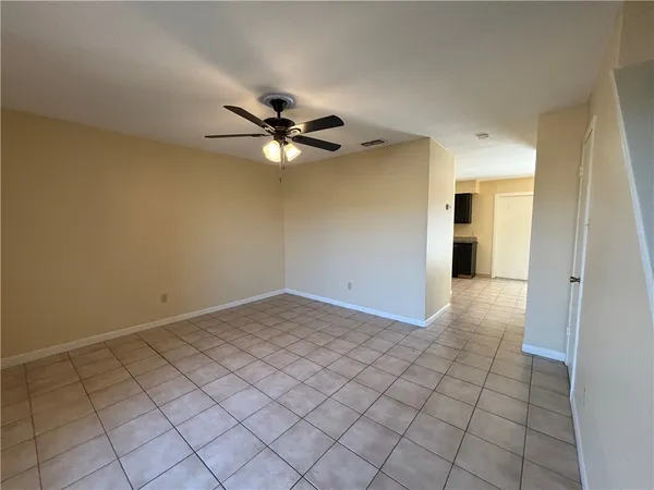 a view of an empty room and chandelier fan