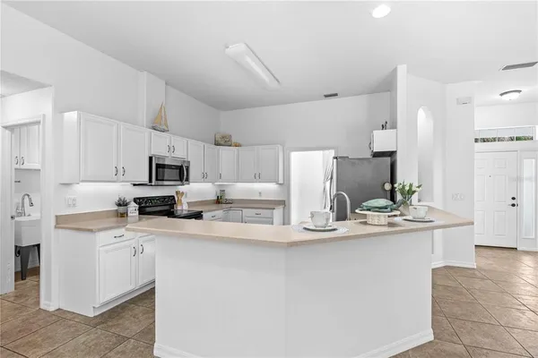 a kitchen with kitchen island a white counter top space cabinets and stainless steel appliances