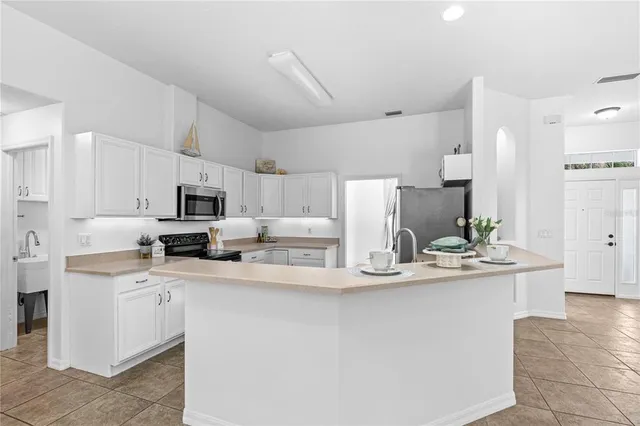 a kitchen with kitchen island a white counter top space cabinets and stainless steel appliances