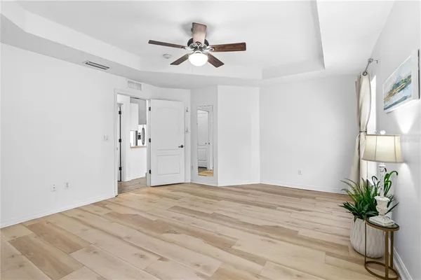 a view of a livingroom with a potted plant a ceiling fan and wooden floor