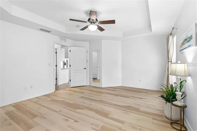 a view of a livingroom with a potted plant a ceiling fan and wooden floor