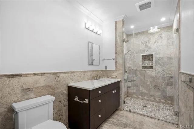a bathroom with a granite countertop sink a toilet a mirror and shower