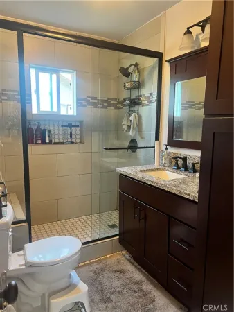 a bathroom with a granite countertop toilet sink and mirror