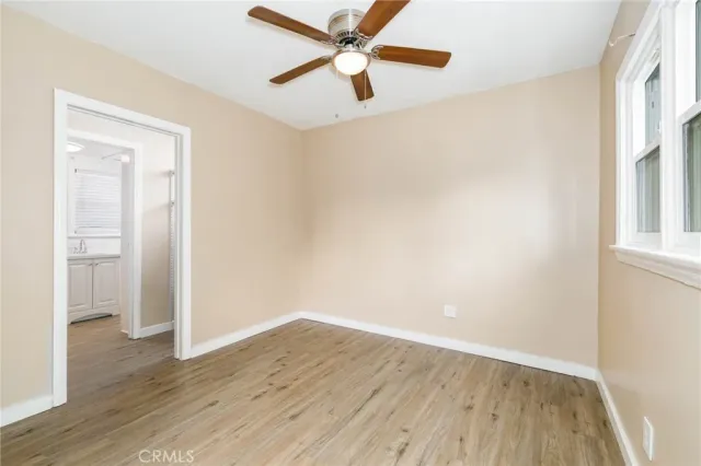 an empty room with wooden floor a ceiling fan and windows