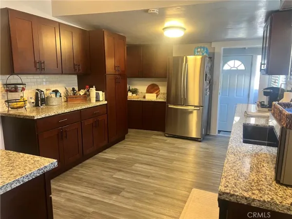 a kitchen with stainless steel appliances granite countertop a sink dishwasher stove and refrigerator with wooden floor