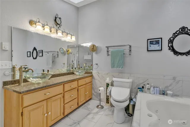 a bathroom with a granite countertop toilet sink and mirror