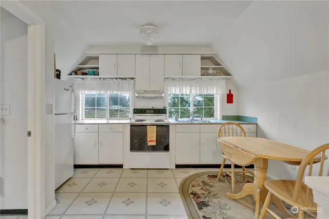 a kitchen with granite countertop white cabinets and white appliances