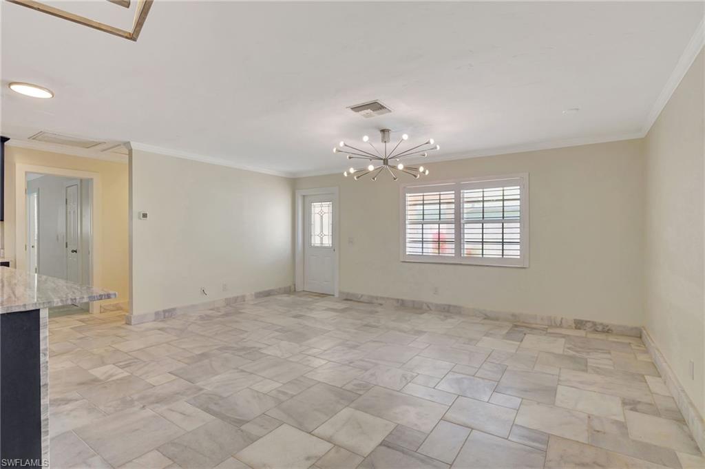 112 Capri Boulevard Naples, FL 34113 - Photo 13 of 39 an empty room with chandelier fan and windows
