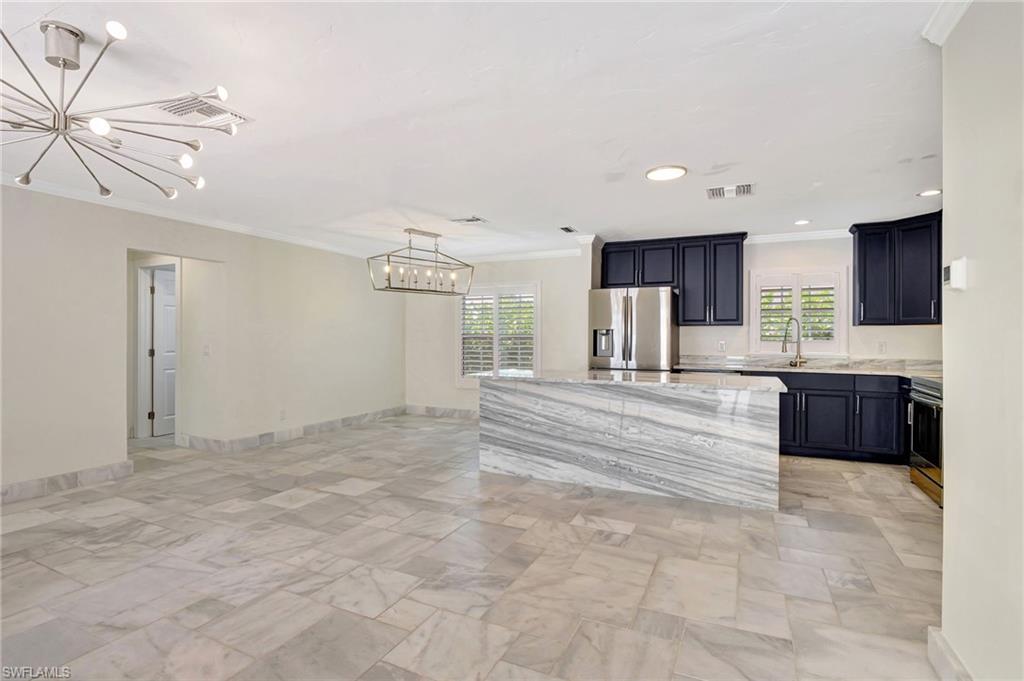 112 Capri Boulevard Naples, FL 34113 - Photo 6 of 39 a large white kitchen with kitchen island a sink stainless steel appliances and cabinets